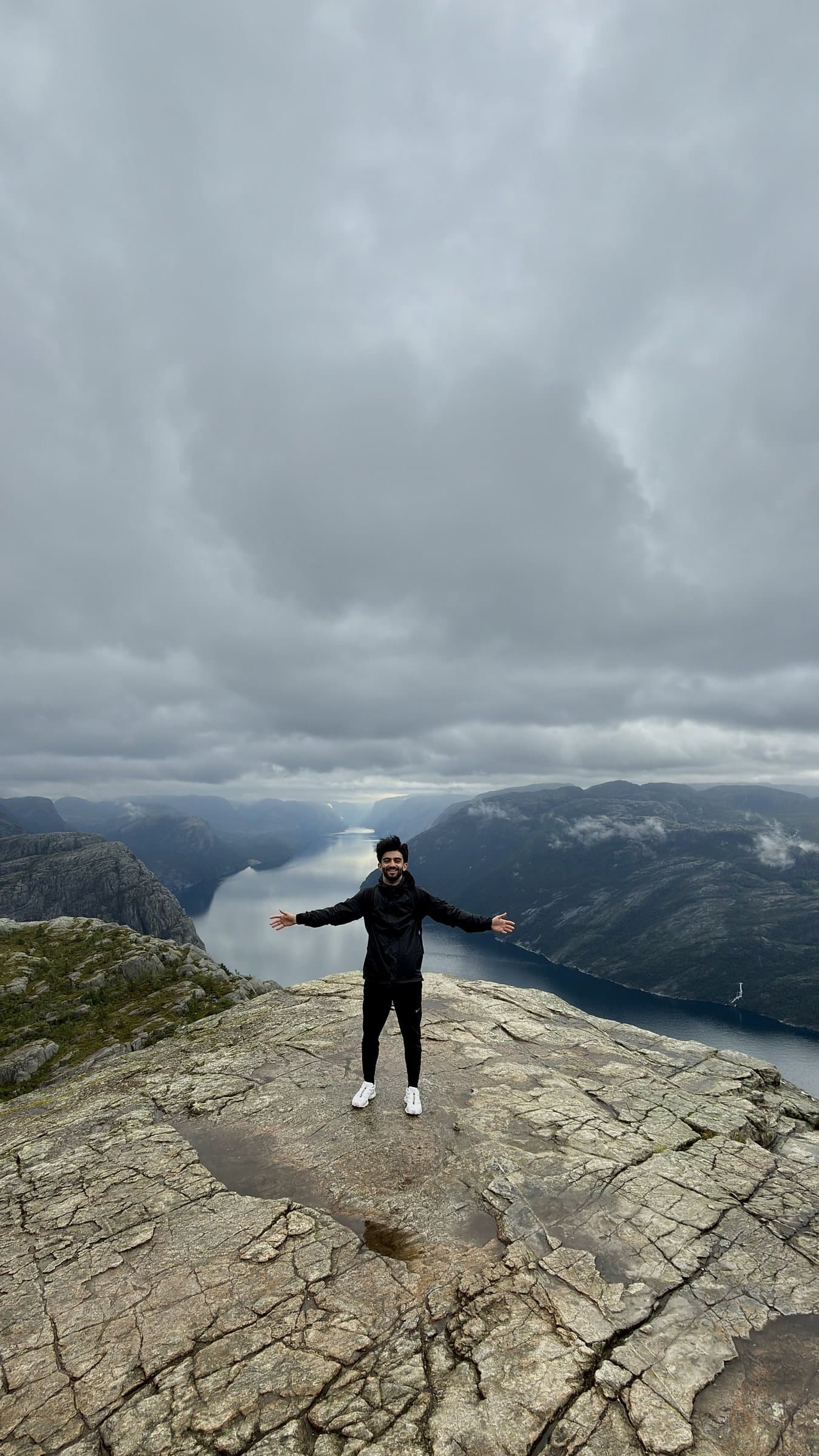 Mahyar standing on top of Preikestolen with his arms open, above the fjord in Norway